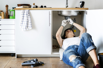 Wall Mural - Woman fixing kitchen sink