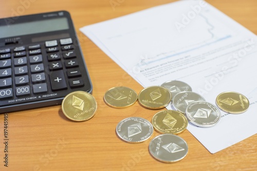 Gold And Silver Ethereum Coins On Brown Wooden Table With Calculator Gold And Silver Ethereum Coins On Brown Wooden Table With Calculator Increasing Graph The