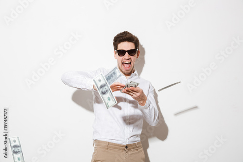 Fotomural Portrait of a happy young man in sunglasses throwing