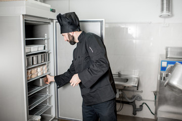 chef cook getting a tray with ingredients from the professional refrigerator in the kitchen