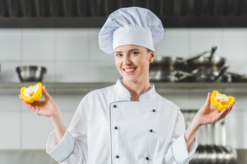 Wall Mural - attractive chef showing halves of bell pepper at restaurant kitchen