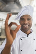 © LIGHTFIELD STUDIOS - smiling african american chef showing okay gesture at restaurant kitchen