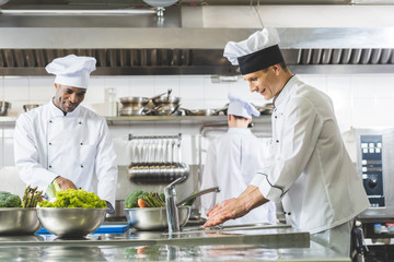 Wall Mural - multicultural chefs working at restaurant kitchen