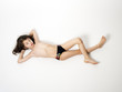 Adorable little boy in a swimsuit lying on the floor, isolated on a light