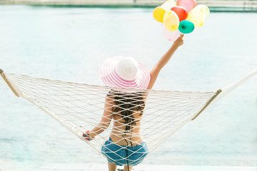 Wall Mural - Vacation concept,Happiness and Enjoying the summer,Rear of young woman relaxing in the hammock with balloons on tropical beach, hot sunny