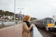 © Wavebreak Media - Young woman standing on railway platform using her mobile phone