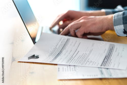 Cuadros en Lienzo Young man writing college or university application form with laptop