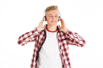 Canvas Print - Satisfied teenager in casual t-shirt 17y listening to melody via wireless earphones with closed eyes and feeling pleasure, isolated over white background