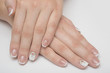 © honcharr - Manicure with rhinestones in the shape of hearts and pink balls on white and red nail Polish on a white background.