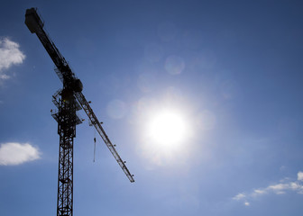 Wall Mural - Tower building crane against the blue sky and sun. Construction of new buildings with a crane. Tower crane