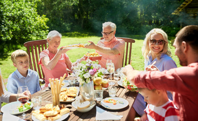 Poster - leisure, holidays and people concept - happy family having festive dinner or summer garden party