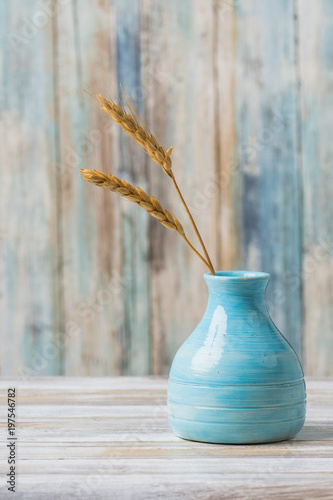 Fotografie, Obraz Blue pottery vase with wheat against rustic wood background