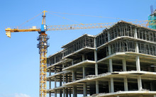 Concrete Highrise Construction Site, With Tower Crane, Blue Sky Background
