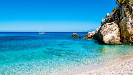 A sailing boat into the turquoise Mediterranean Sea, at San Vito Lo Capo, Sicily, Italy.