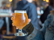 Woman holding light beer snifter in bar/brewery