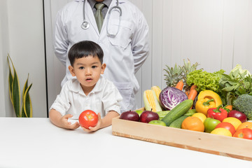 Wall Mural - Healthy and nutrition concept. Kid learning about nutrition with doctor to choose eating fresh fruits and vegetables.Young asian boy holding tomato.