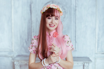 Beautiful young woman doll in a pink dress, with a lollipop, lolita. Japanese street fashion. Portrait.