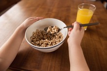 Girl Having Breakfast Cereal And Juice On Table