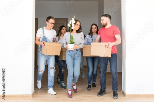Fotografía Friends go into a new house holding cardboard boxes with things in their hands