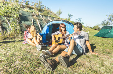 Wall Mural - Friends group having fun outdoor cheering at picnic camp with vintage guitar - Young people enjoying summer time together at countryside party - Youth travel friendship concept - Warm bright filter