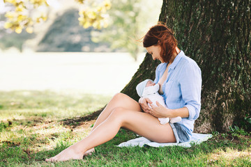 Mother breastfeeding newborn baby child on nature