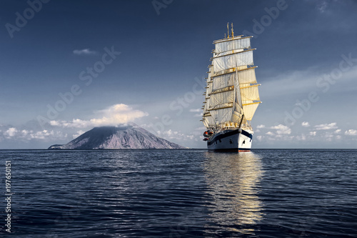 Sailing ship on the background of the island with a volcano. Cruises. Yachting. Sailing © Alvov