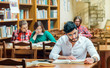 © proimagecontent - Bearded student man wears white shirt studying with books in the library