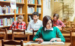 © proimagecontent - Beautiful student girl wears green sweater studying with books in the library