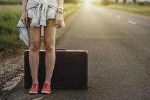 Low Section Of Woman Standing By Suitcase On Road