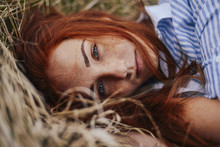 Close-up Portrait Of Teenage Girl With Red Head Lying On Grassy Field
