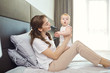 © Studio Romantic - Mother playing with baby on the bed. Mothers Day.