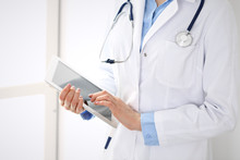 Woman Doctor Using Tablet Computer While Standing Straight In Hospital Closeup. Healthcare, Insurance And Medicine Concept