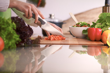 Close Up of human hands cooking vegetable salad in kitchen on the glass table with reflection. Healthy meal, and vegetarian food concept