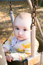 Close-up Of A Baby Girl Sitting On Swing