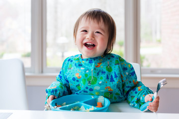 Wall Mural - Happy toddler boy with a big smile eating food