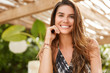 © WHstudio Leushin N - Brunette smiling female sits in outdoor cafeteria, has broad smile, has good rest, has satisfied expression, rests in tropical resort country. Cute young woman rests in terrace cafe. Positiveness