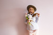 © AnastazjaSoroka - A young beautiful girl with blond dissolved long hair, a felt hat on her head, keeps spring flowers in her hands on a sunny day. Women's Day.