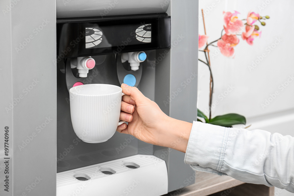 Woman filling cup from water cooler, closeup