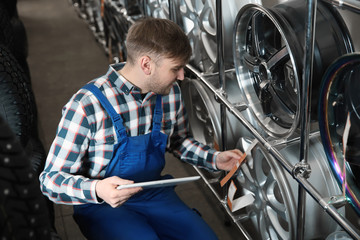 Wall Mural - Young male mechanic with tablet computer in automobile service center