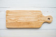 Top view of unused brand new brown handmade wooden cutting board on white wooden table background