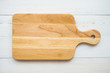 Top view of unused brand new brown handmade wooden cutting board on white wooden table background