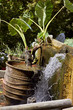 old clay pot with green plant and decorative small waterfall fountain in greek village Argiroupoli, Crete, Greece