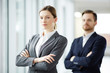 © pressmaster - Serious young businesswoman in formalwear crossing her arms on chest and looking at camera with colleague on background