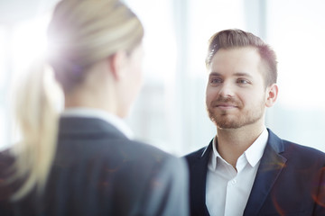 Wall Mural - Young confident manager looking at colleague while listening to her speech or opinion at meeting