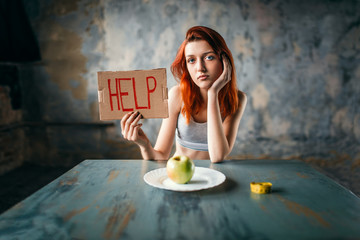 Woman holds help sign against plate with apple