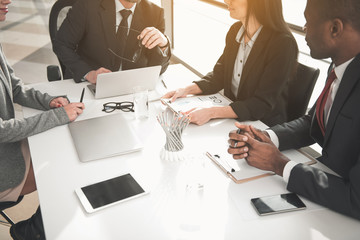 Canvas Print - Group of people taking seat at meeting and conversing. Gadgets and documents are on table