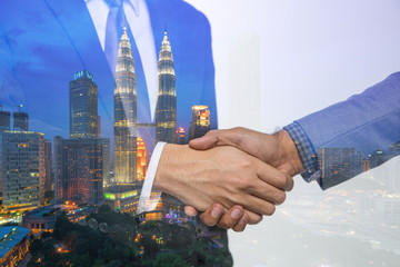 Double Exposure of a businessman handshake on Kuala lumpur cityscape skyscraper Malaysia background.