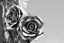 Two Metal Roses On A Background Of Blue Sky