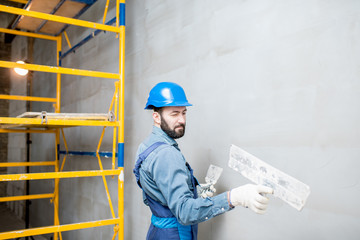 Wall Mural - Plasterer in blue working uniform plastering the wall indoors