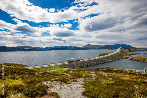 Fotografie, Obraz Truck rushes down the highway in the background Atlantic Ocean Road Norway